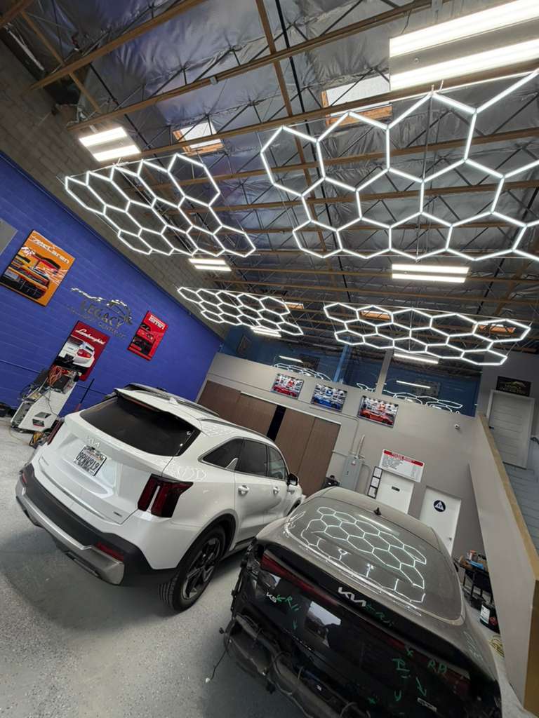 Modern auto body shop with hexagonal lighting and vehicles